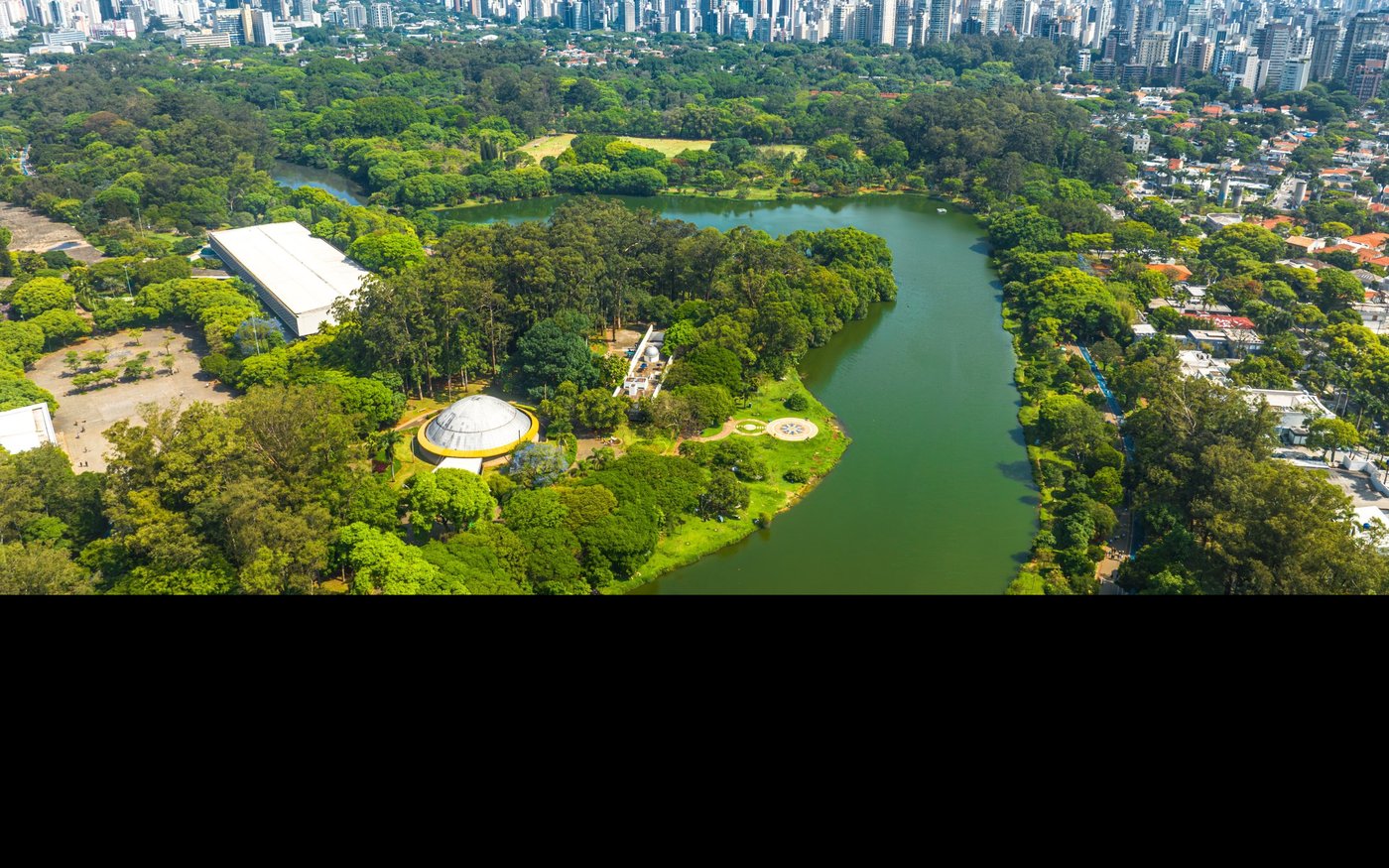 Parque Ibirapuera visto do alto, com o lago e o skyline da Vila Mariana