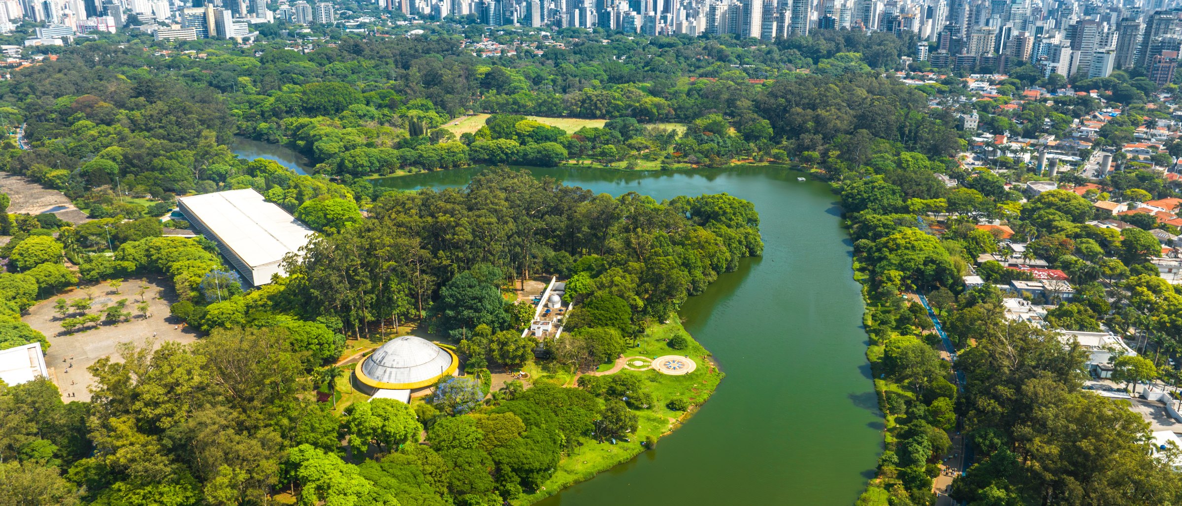Parque Ibirapuera visto do alto, com o lago e o skyline da Vila Mariana