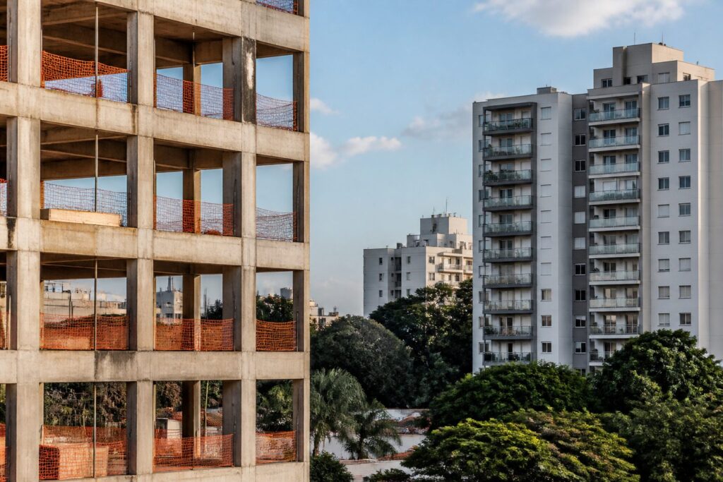 Edifício em construção com estrutura aparente ao lado de prédios residenciais concluídos